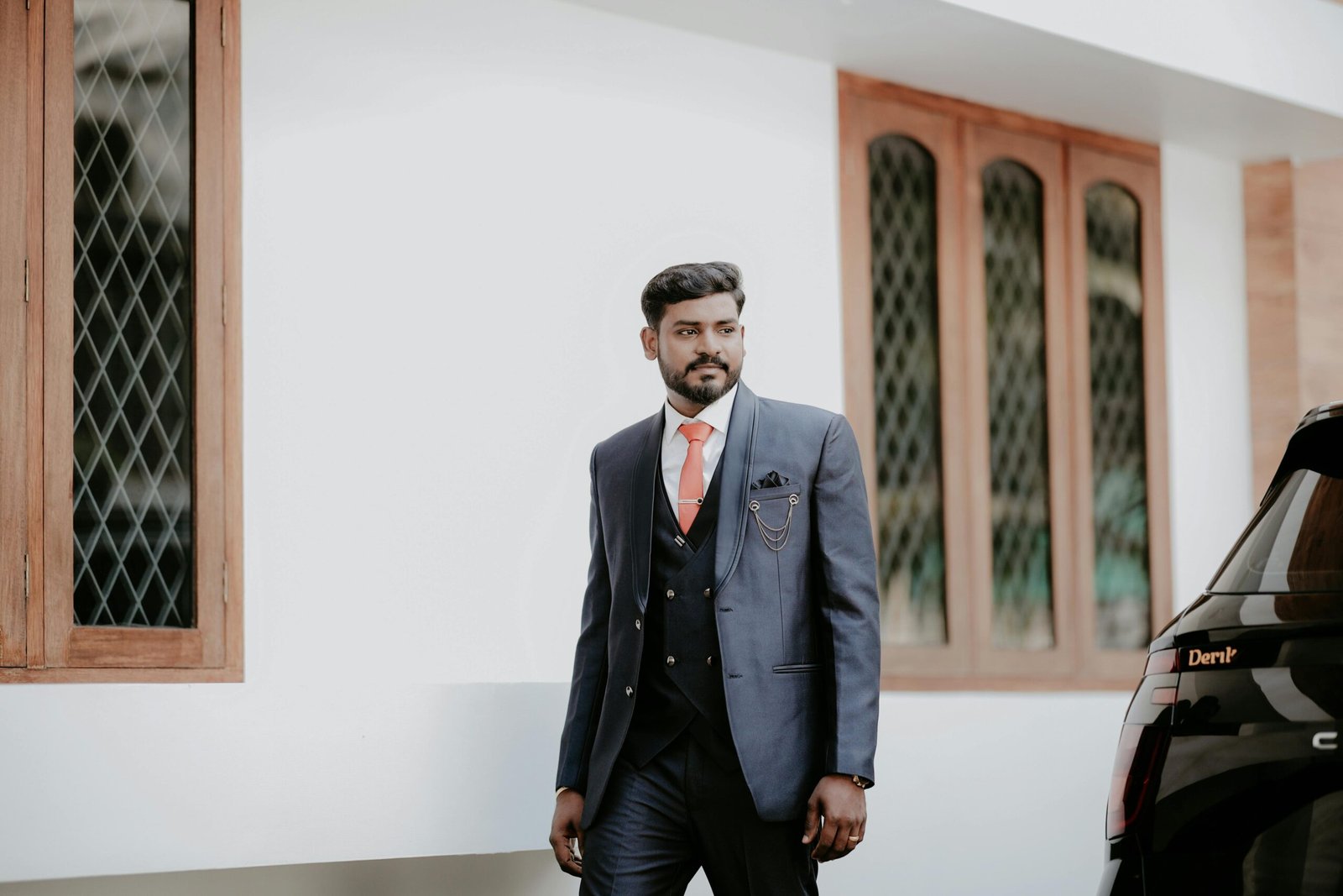 Indian groom in a stylish blue suit, posing outdoors with a confident expression.